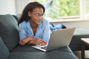 woman laying on a couch on a computer